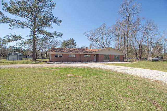 view of front of home featuring gravel driveway, brick siding, a chimney, and a front lawn