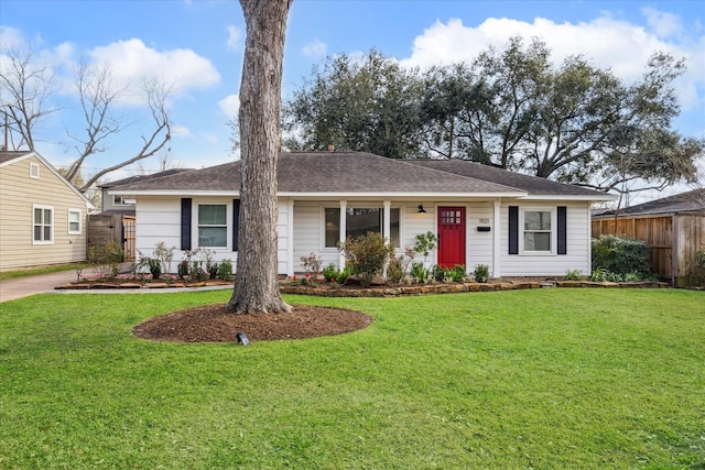 ranch-style home with roof with shingles, fence, and a front yard