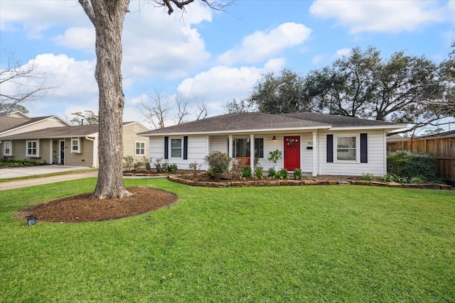 ranch-style home featuring driveway, fence, and a front yard