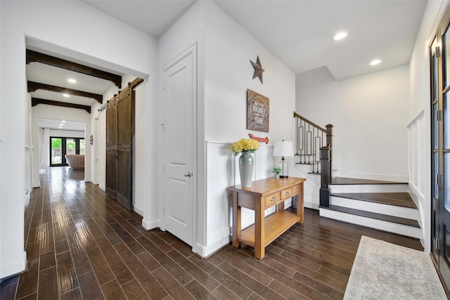 entryway featuring dark wood-style floors, stairway, beamed ceiling, and a barn door