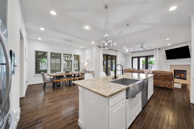 kitchen featuring a sink, open floor plan, a glass covered fireplace, appliances with stainless steel finishes, and wood tiled floor