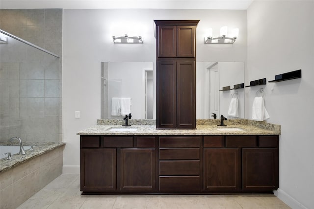 full bath featuring double vanity, baseboards, tiled bath, and a sink