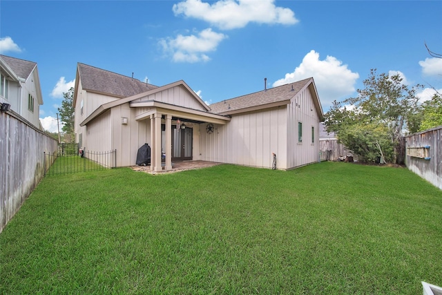 back of property with a lawn, board and batten siding, a fenced backyard, and a patio