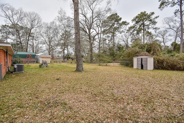 view of yard featuring an outbuilding, cooling unit, fence, and a storage unit