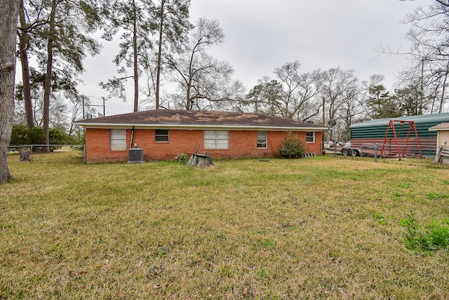 back of house featuring brick siding, a lawn, cooling unit, and fence