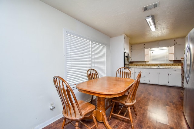 dining space featuring a textured ceiling, dark wood-type flooring, visible vents, and baseboards