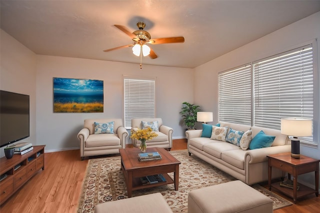 living area with ceiling fan, light wood-style flooring, and baseboards