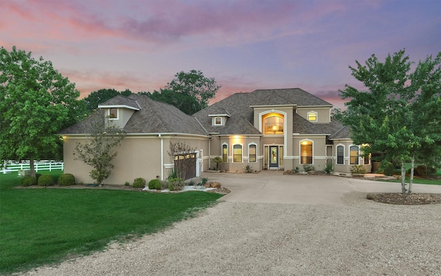 french provincial home with a garage, concrete driveway, fence, and stucco siding