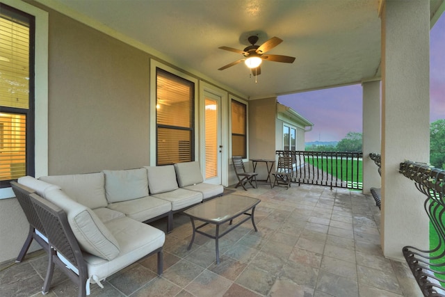 patio terrace at dusk featuring a ceiling fan and an outdoor living space