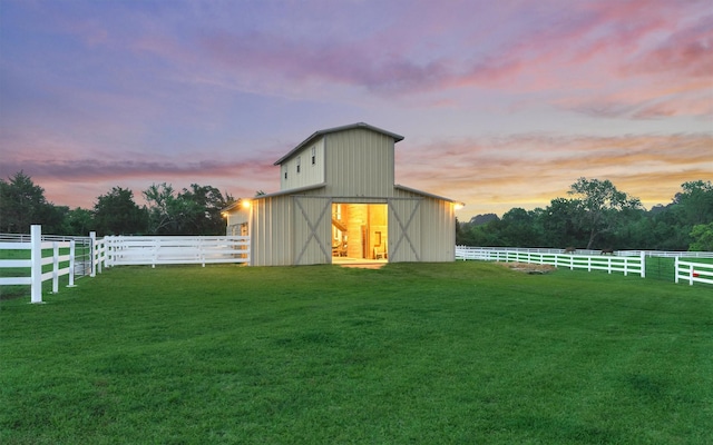 view of barn with a lawn and fence