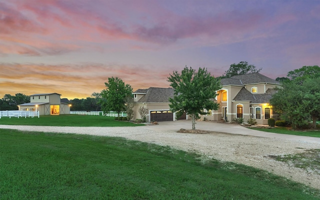 view of front of house with stucco siding, a shingled roof, a front yard, fence, and driveway