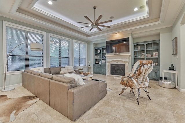 living area with a raised ceiling, crown molding, and a premium fireplace