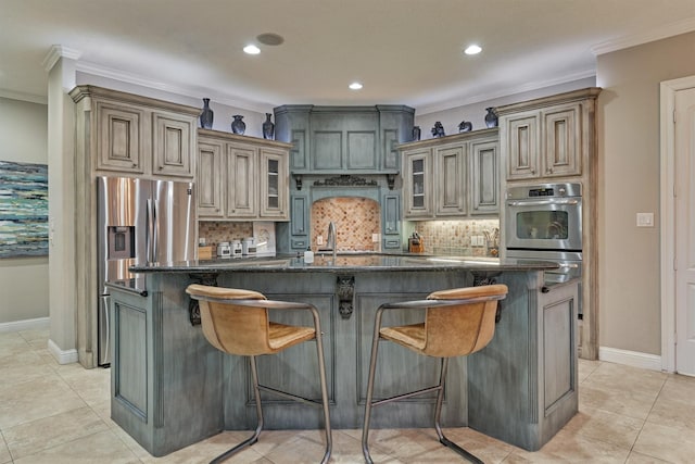 kitchen featuring tasteful backsplash, a center island with sink, a kitchen breakfast bar, and crown molding