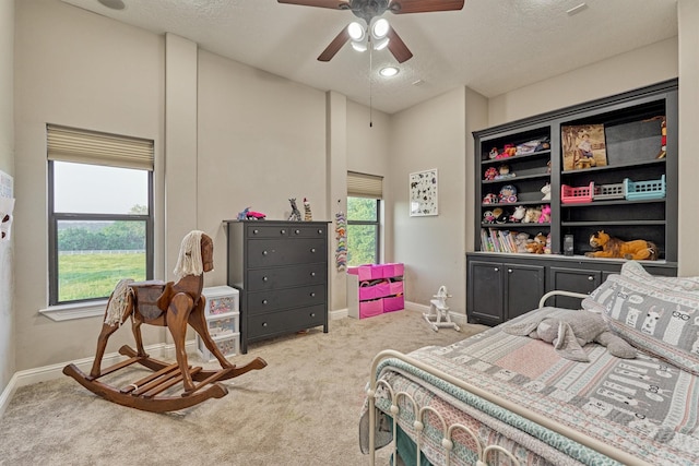 carpeted bedroom featuring ceiling fan, a textured ceiling, and baseboards