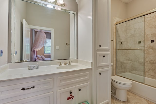 bathroom featuring tile patterned flooring, combined bath / shower with glass door, vanity, and toilet