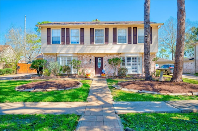 colonial inspired home featuring fence and brick siding