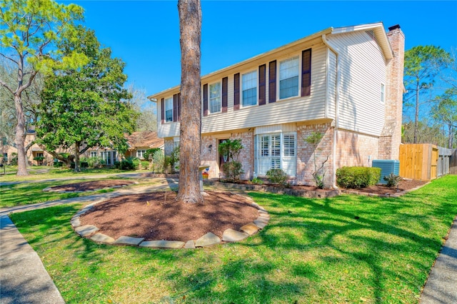 view of front of house with a front yard, brick siding, fence, and a chimney