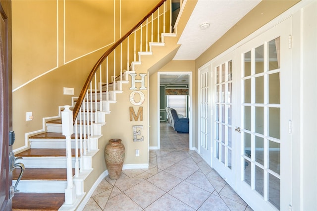 staircase with french doors, tile patterned flooring, and baseboards