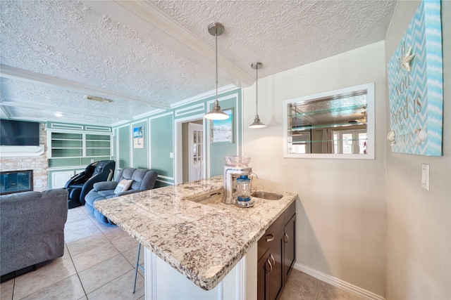 kitchen with a textured ceiling, a breakfast bar, a fireplace, open floor plan, and light stone countertops