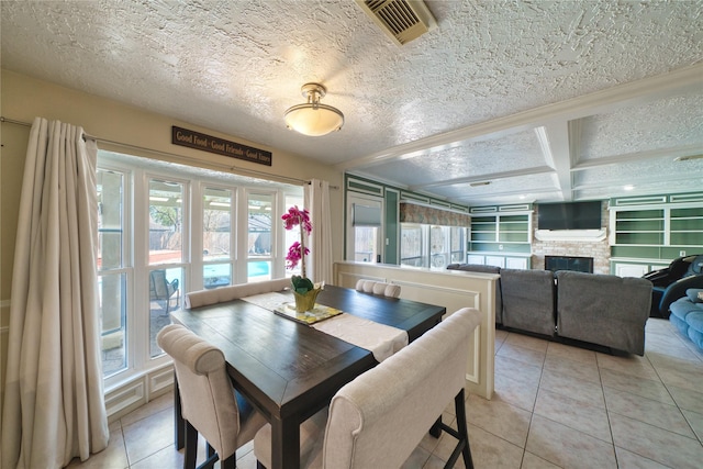 dining space featuring light tile patterned floors, visible vents, coffered ceiling, a textured ceiling, and a fireplace