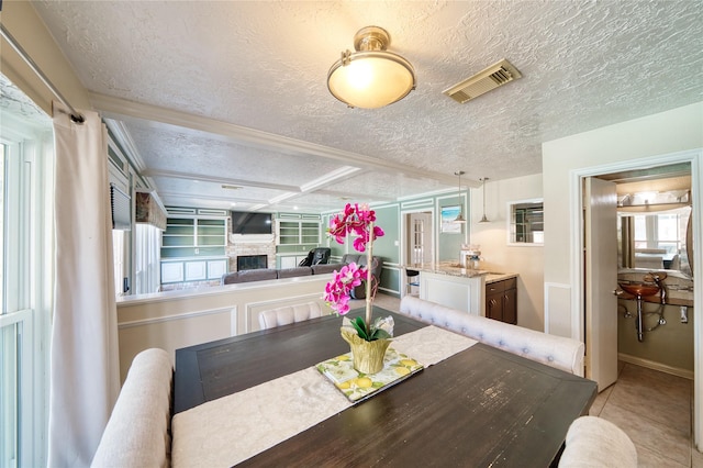 dining area featuring a fireplace, visible vents, a textured ceiling, and light tile patterned flooring