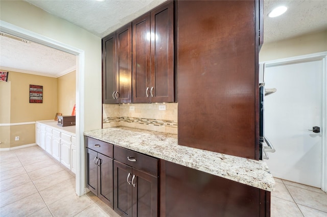 kitchen featuring tasteful backsplash, a textured ceiling, dark brown cabinets, and light tile patterned floors