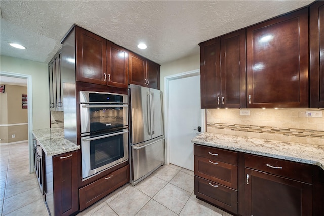 kitchen featuring light tile patterned floors, stainless steel appliances, backsplash, and light stone countertops