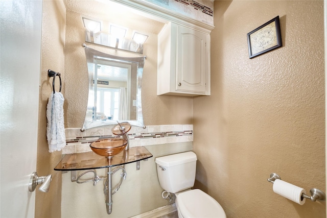 half bath featuring toilet, tile walls, and a textured wall