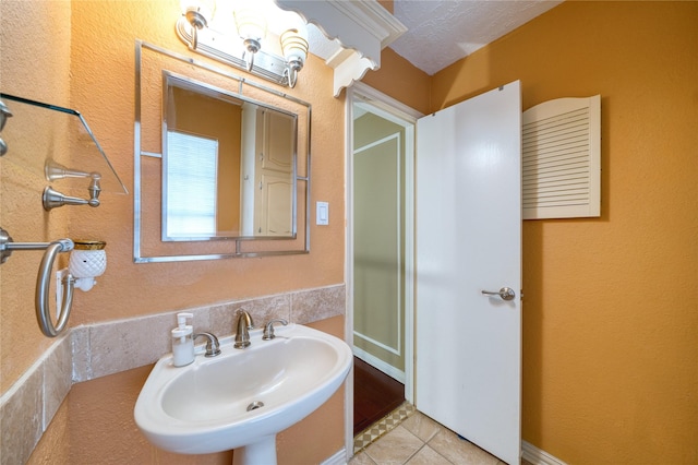 bathroom with a textured ceiling, tile patterned flooring, and a sink