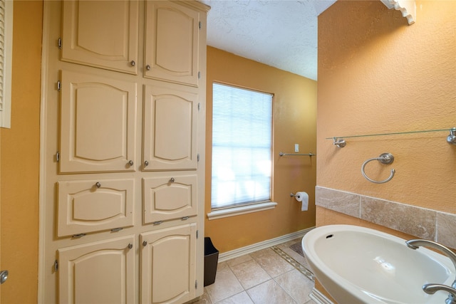 bathroom with a textured ceiling, baseboards, and tile patterned floors