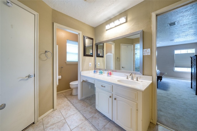 full bath featuring toilet, a textured ceiling, visible vents, and a sink