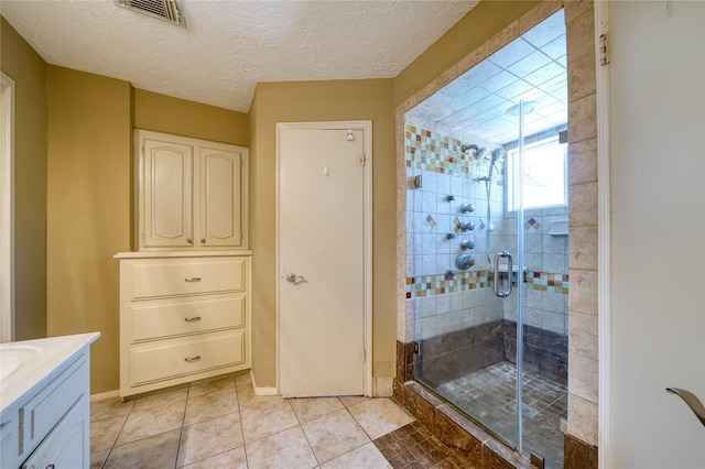 full bath with visible vents, a stall shower, a textured ceiling, vanity, and tile patterned flooring