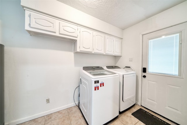 laundry room featuring cabinet space, light tile patterned floors, baseboards, and washer and clothes dryer