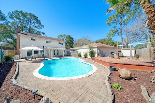 view of swimming pool with a deck, a patio, an outbuilding, a fenced backyard, and a fenced in pool