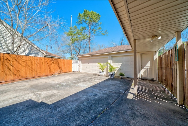 view of patio with an attached garage, fence, and concrete driveway