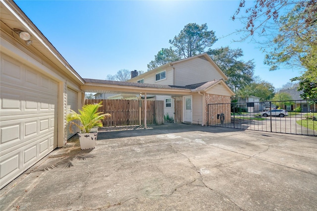 view of front facade with concrete driveway, fence, an attached garage, and a gate