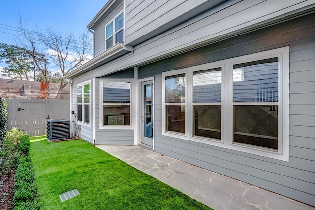 exterior space featuring fence, a lawn, and central AC unit