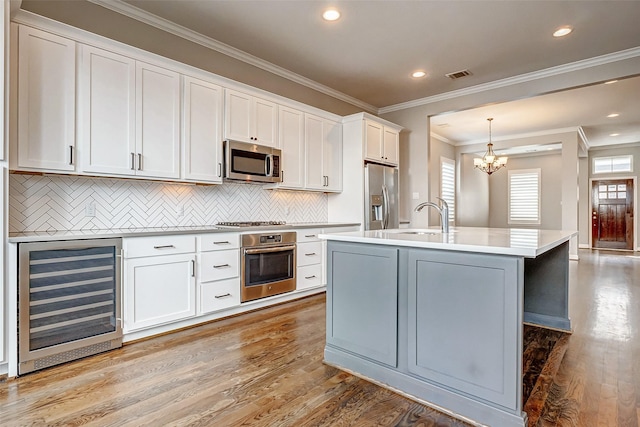 kitchen featuring wine cooler, stainless steel appliances, a sink, visible vents, and light countertops