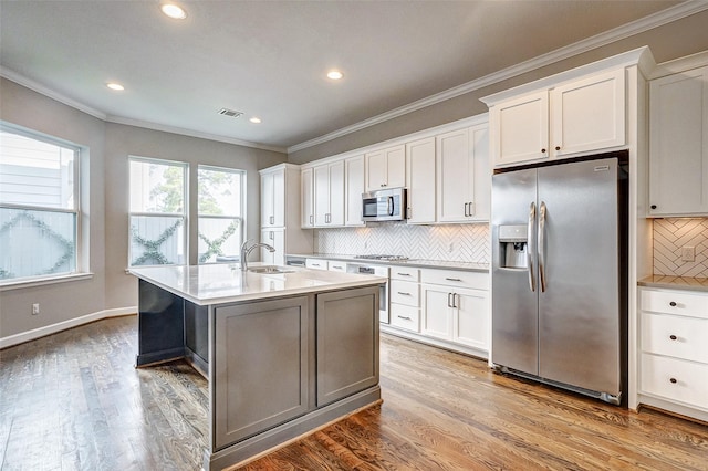 kitchen with crown molding, stainless steel appliances, light countertops, light wood-style flooring, and a sink