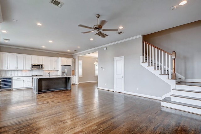 kitchen with wine cooler, visible vents, appliances with stainless steel finishes, open floor plan, and an island with sink