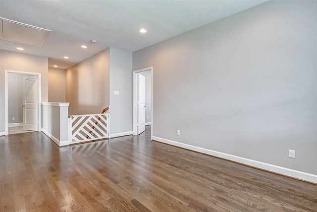 spare room featuring recessed lighting, wood finished floors, attic access, and baseboards