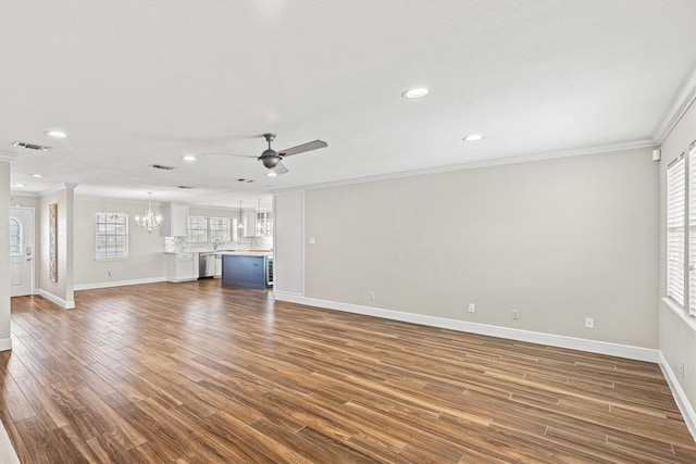 unfurnished living room with ceiling fan with notable chandelier, dark wood-type flooring, baseboards, and crown molding