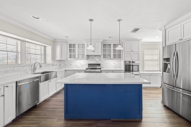 kitchen with a center island, stainless steel appliances, dark wood-type flooring, ornamental molding, and a sink