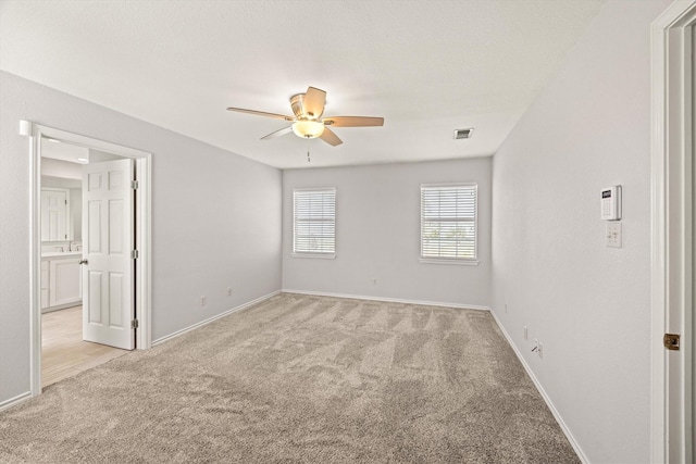 spare room featuring light carpet, baseboards, visible vents, and a ceiling fan