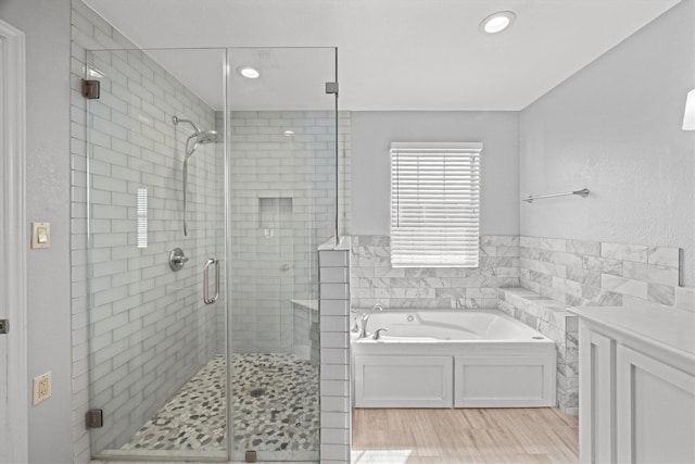 bathroom featuring a stall shower, wood finished floors, a bath, and tile walls