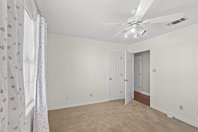 unfurnished bedroom with carpet floors, baseboards, visible vents, and a ceiling fan