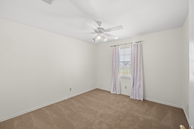 carpeted spare room featuring a ceiling fan and baseboards