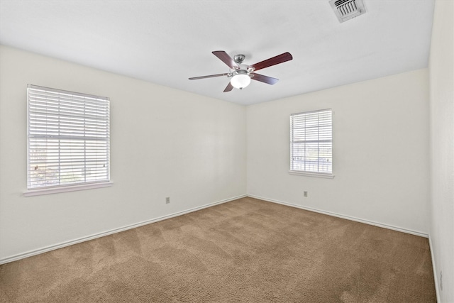 carpeted empty room with visible vents, ceiling fan, and baseboards