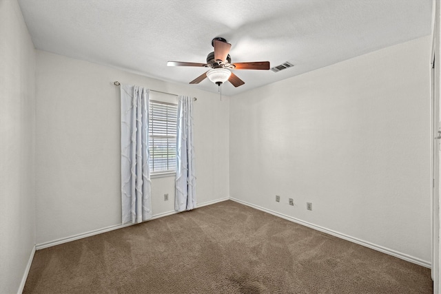 carpeted empty room featuring ceiling fan, a textured ceiling, visible vents, and baseboards