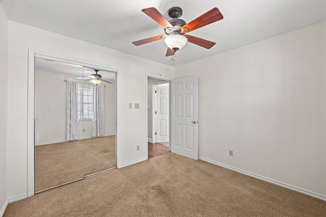 unfurnished bedroom featuring carpet floors, a ceiling fan, baseboards, and a closet